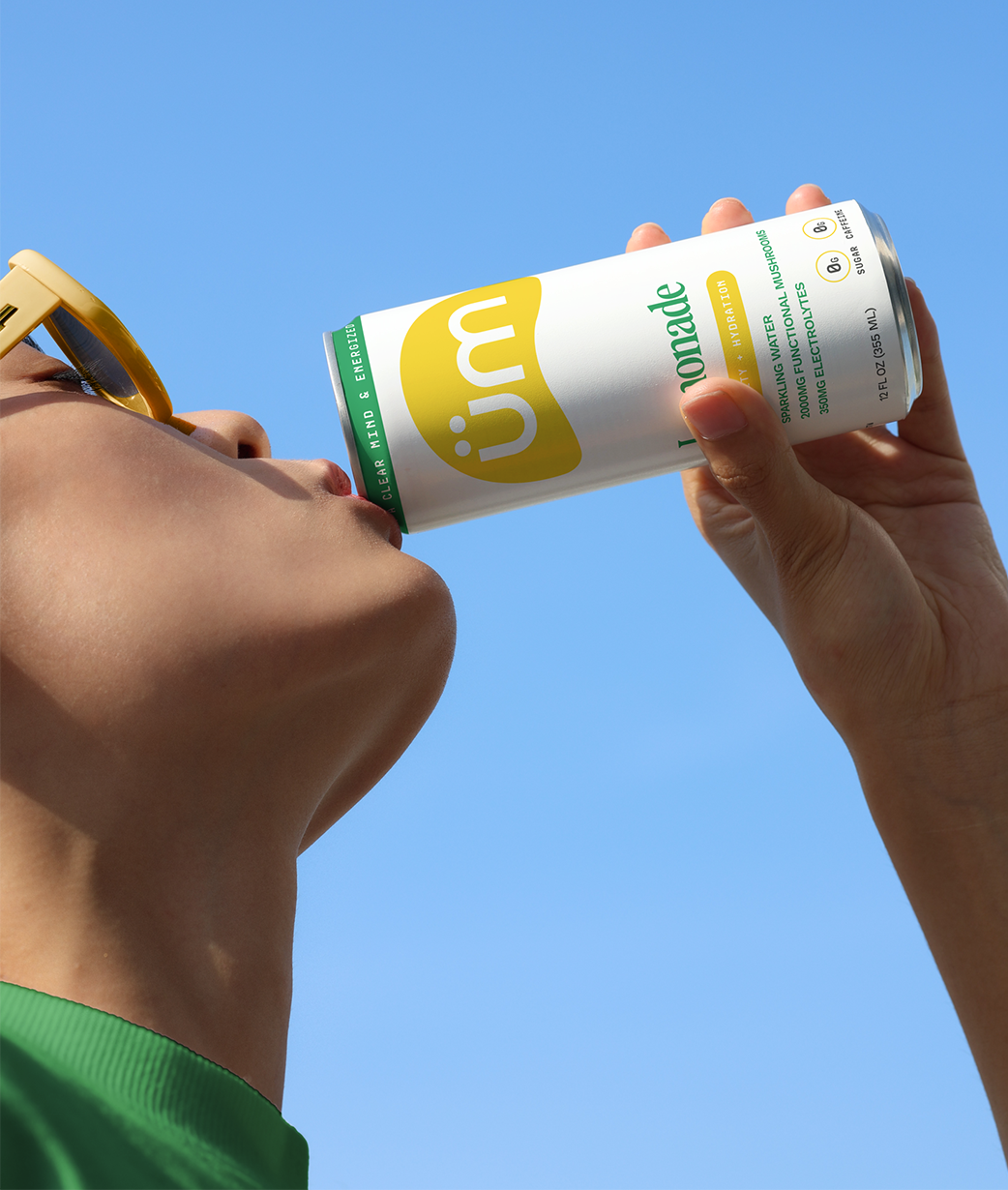 Woman wearing sunglasses taking a sip from Lemonade üm.